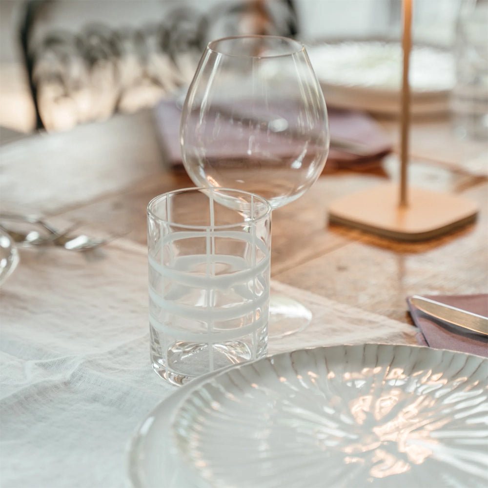 transparent eau glass avec decorazisuri bianche et tigemed glass transparent appoggiati sur white nappe à côté de decorated plate et lilac napkin