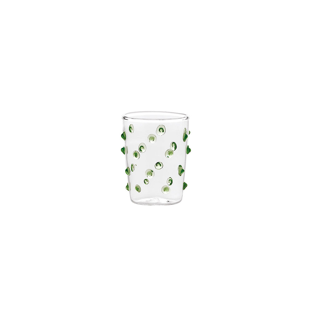 Verre transparent en verre avec petites sphères décoratives vertes incrustées sur la surface, fond blanc.