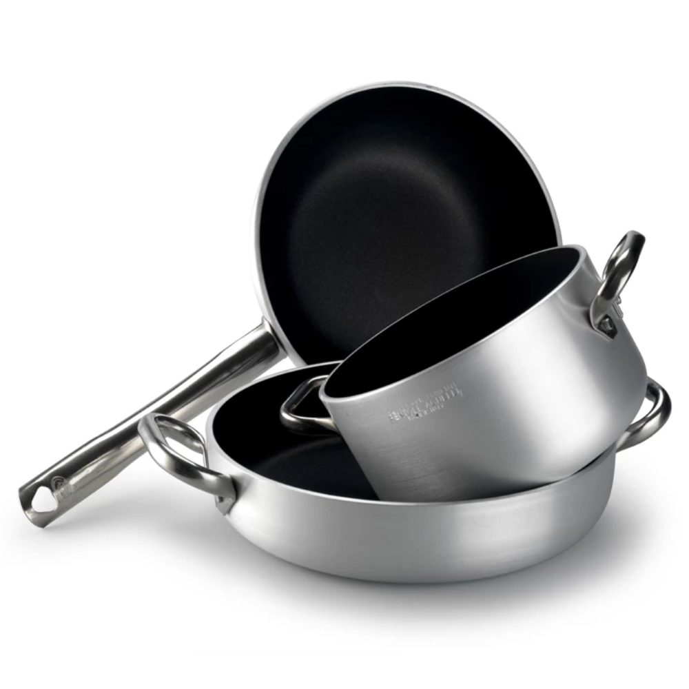 Set composé de poêle, casserole et sauteuse en métal argenté avec intérieur antiadhésif noir, manches métalliques, fond blanc.