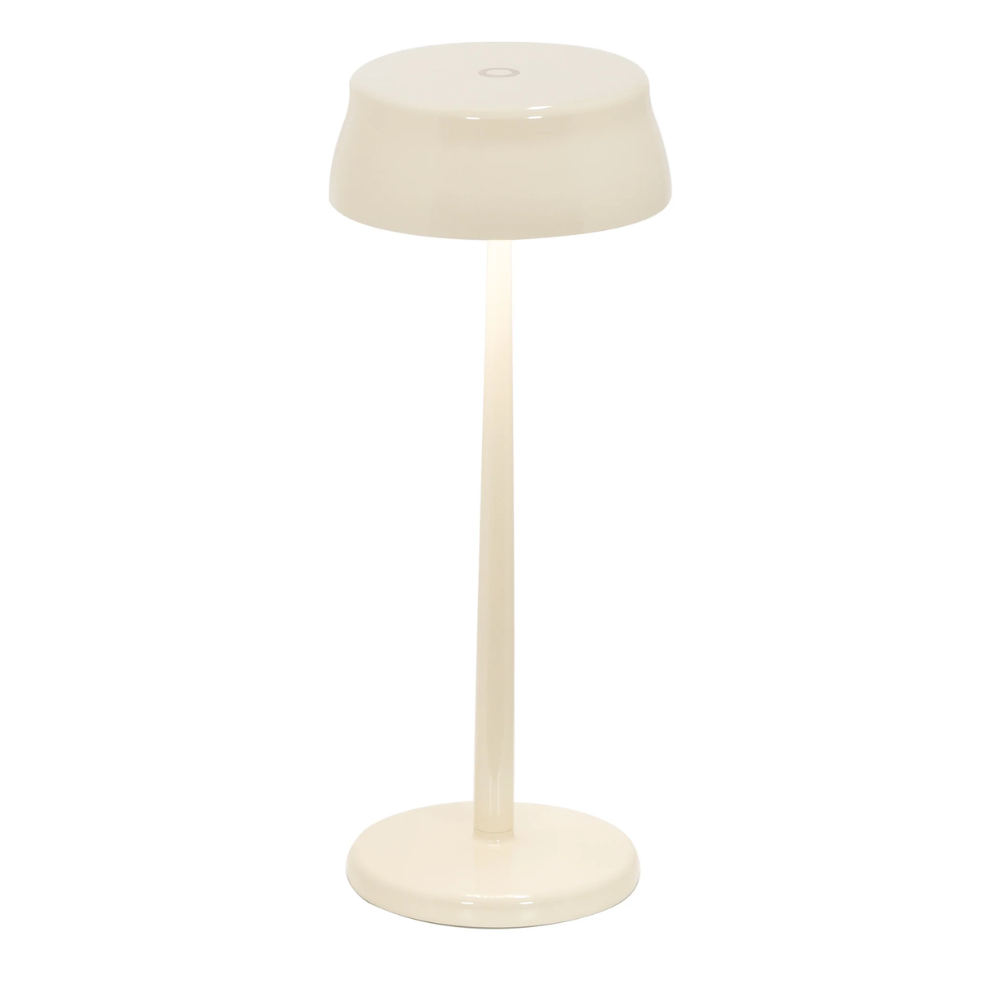 Lampe de table ivoire brillante avec abat-jour et base ronde en matériau rigide, sur fond blanc neutre.
