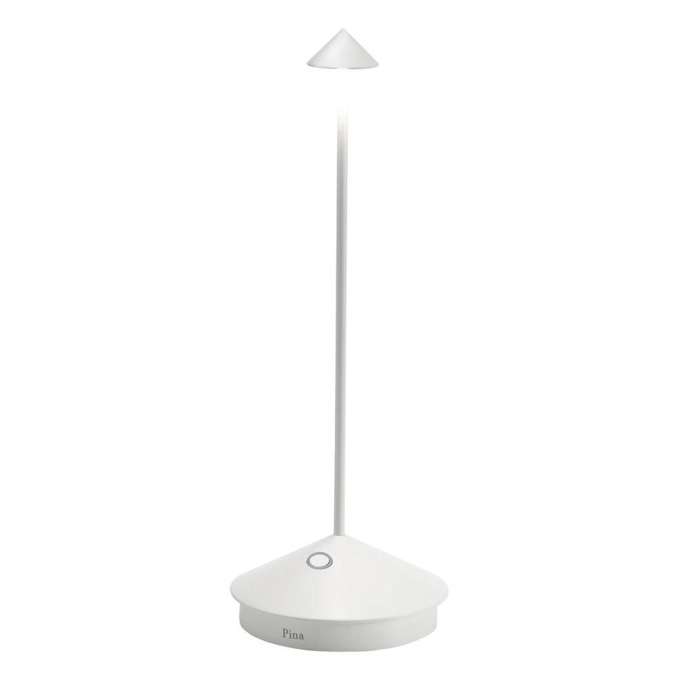 lampada da tavolo bianca con base triangolare smussata, fusto sottile e paralume a forma di cono rovesciato, ambiente neutro