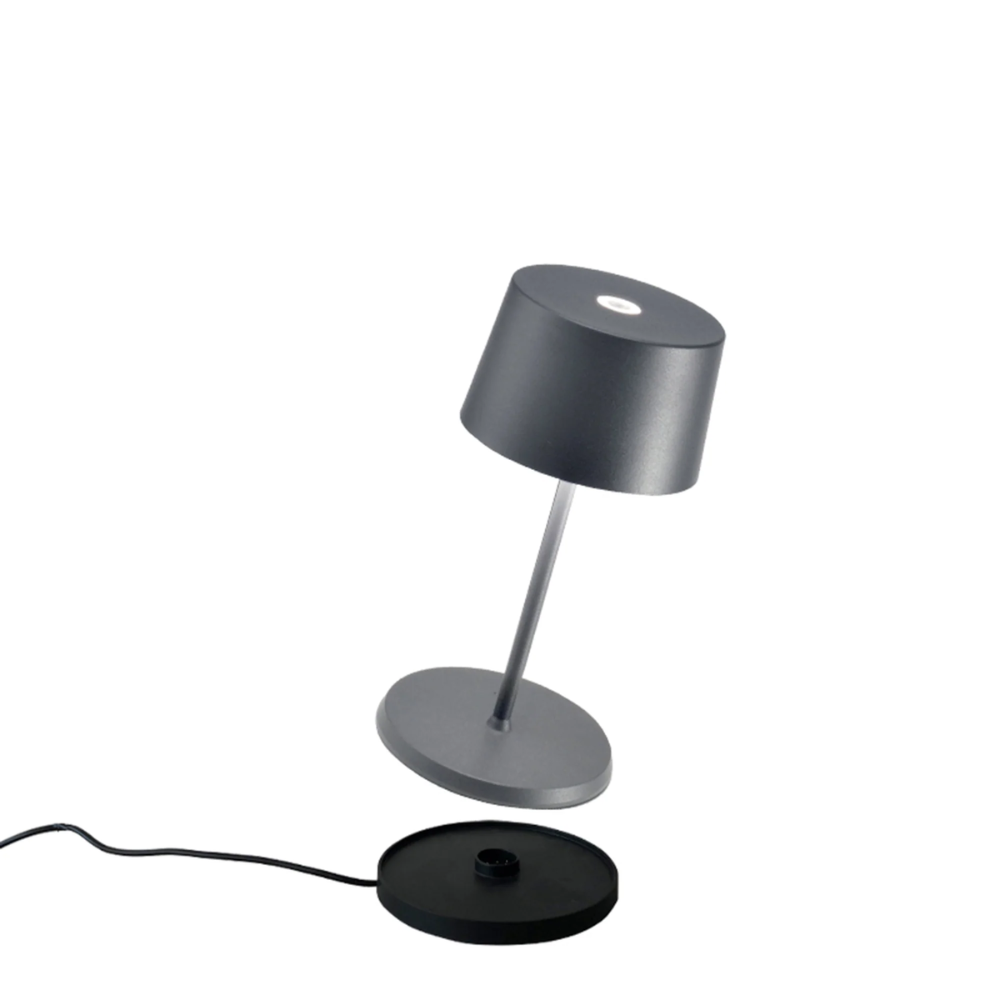 Lampe de table grise avec abat-jour cylindrique, base ronde et tige centrale fine, matériau métallique mat, sur fond blanc