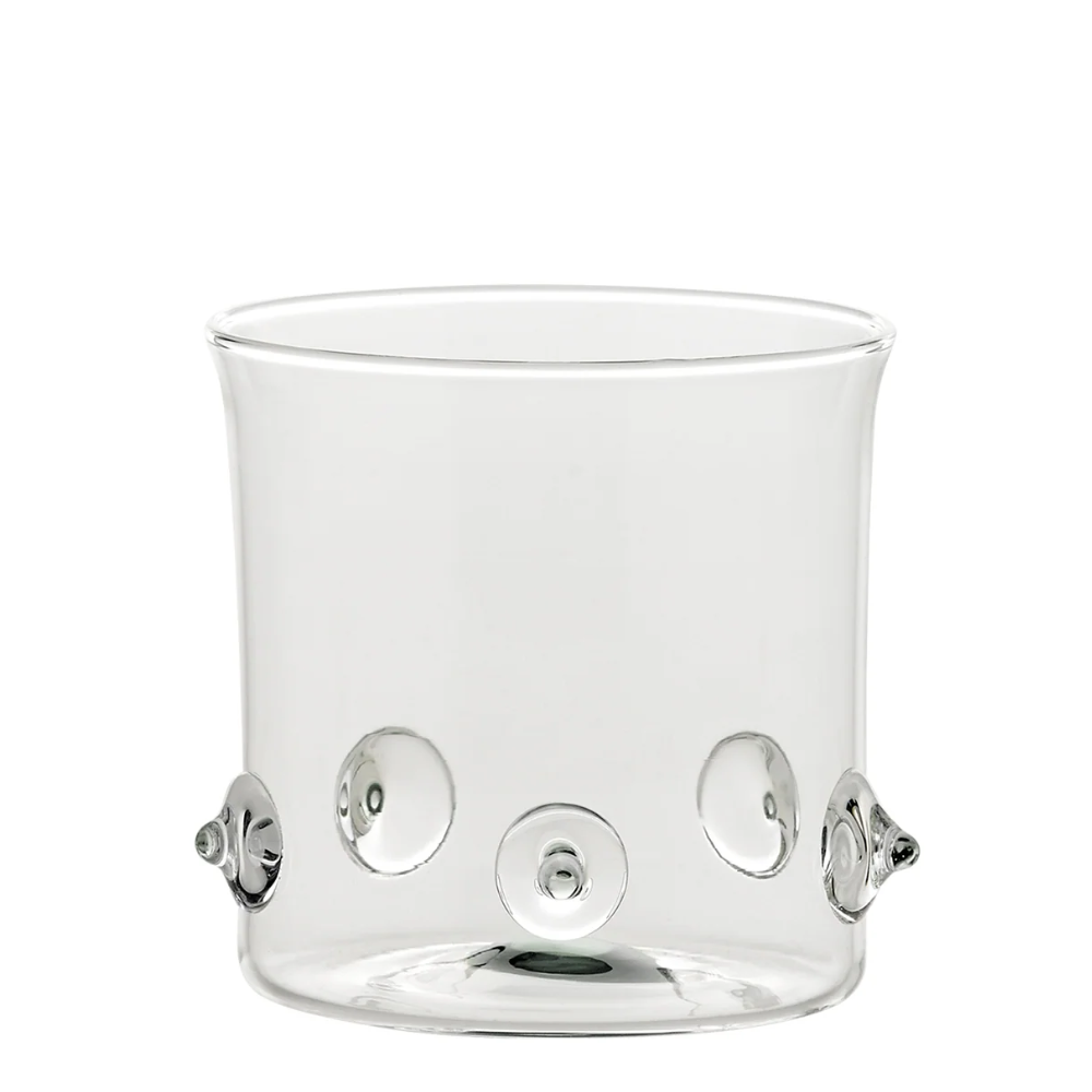 Bicchiere trasparente in vetro con base cilindrica e applicazioni decorative tonde in rilievo trasparente su fondo bianco.