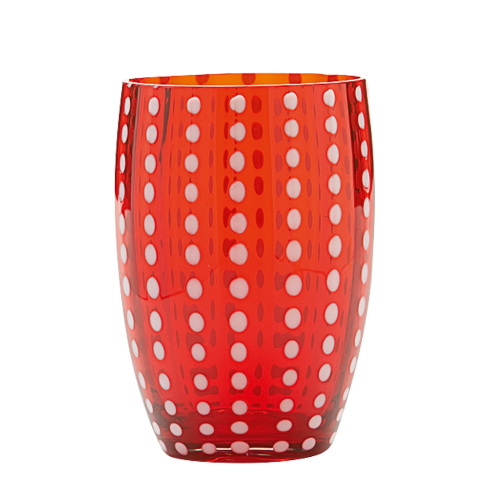 Verre rouge transparent en verre avec décorations à pois blancs disposées verticalement sur fond blanc.