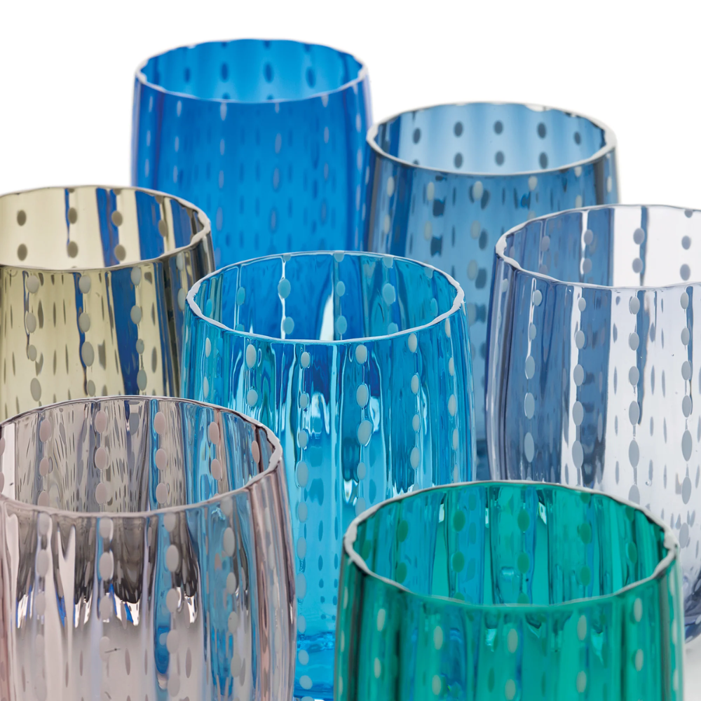 Set di sette bicchieri di vetro colorati con decorazione a pois trasparente su fondo bianco.