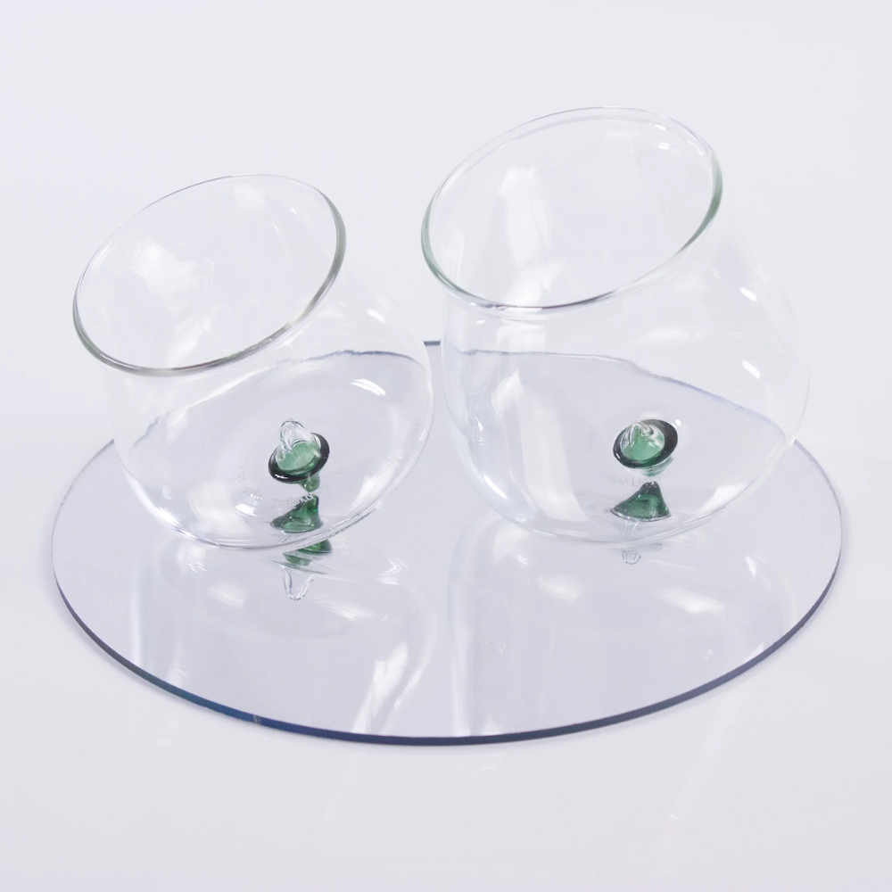 twee transparante glazen met groen decoratief voetstuk op wit reflecterend oppervlak