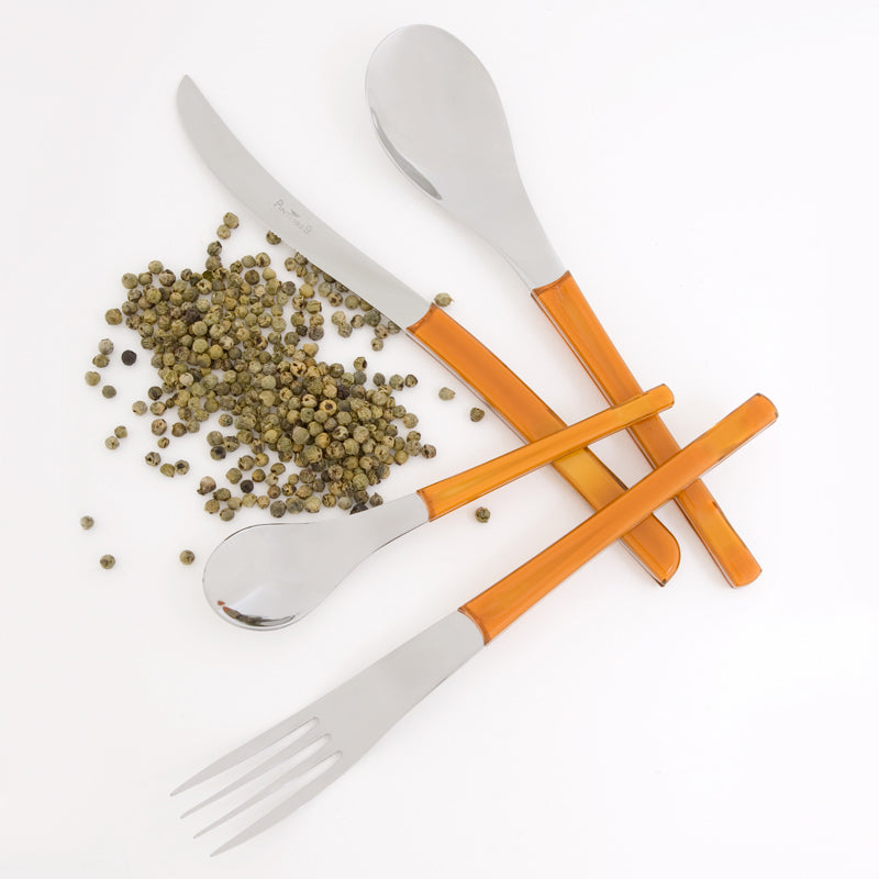 Cuchillo, cuchara, tenedor y cucharilla con mangos naranjas translúcidos y pimienta verde esparcida sobre fondo