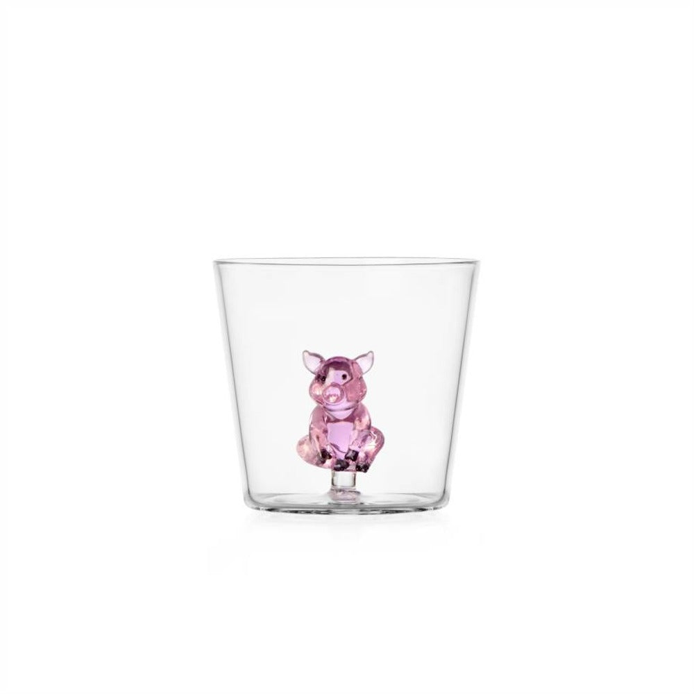 Transparent tumbler with a pink glass piglet inside, on white background.