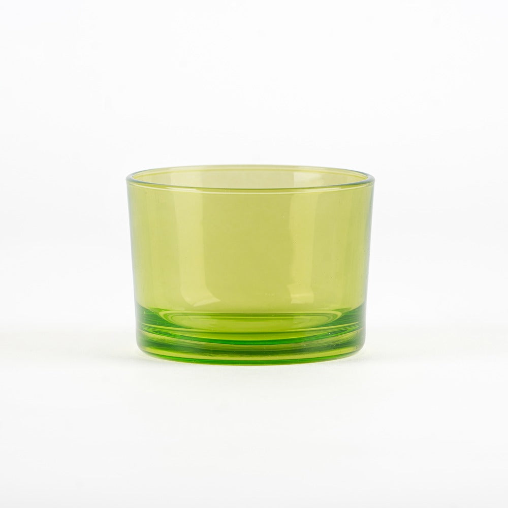 Bicchiere cilindrico in vetro verde chiaro, con base più scura e superficie liscia, su sfondo bianco.