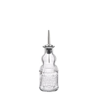 Transparante glazen dispenser met metalen dop, gevormd en versierd met kleine decoratieve bellen.