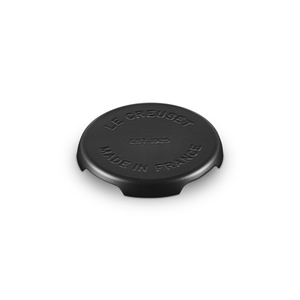 Coperchio circolare nero con scritte in rilievo, "LE CREUSET EST. 1925 MADE IN FRANCE", su sfondo bianco.
