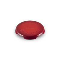 Coperchio rotondo di colore rosso, in materiale ceramico lucido, con incisioni "LE CREUSET" e "MADE IN FRANCE".