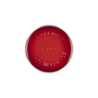 Tegame rotondo di colore rosso, in ghisa smaltata, con scritte "LE CREUSET" e "MADE IN FRANCE" in rilievo. Fondo liscio.