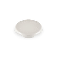 Tappo rotondo in ceramica bianca con incisi "LE CREUSET" e "MADE IN FRANCE", superficie liscia e leggermente lucida.