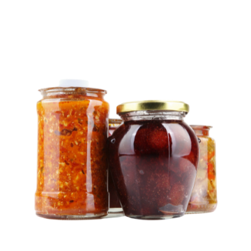 Tre vasetti di vetro con coperchio, uno contiene salsa rossa, uno fragole scure in sciroppo e uno altra salsa