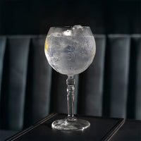 Transparant glas met ijzige drink en citroenschijf op donker oppervlak, achtergrond met donkerblauwe vulling.