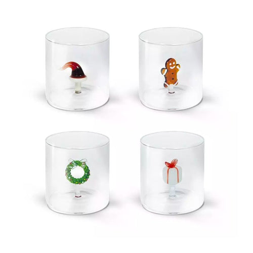 Quattro bicchieri trasparenti con piccoli oggetti natalizi interni: cappello di Babbo Natale, omino di pan di zenzero, corona verde e regalo bianco