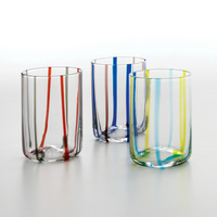 Tre bicchieri trasparenti in vetro con bordi decorati da sottili righe verticali colorate rosse, verdi, blu, gialle su sfondo bianco.