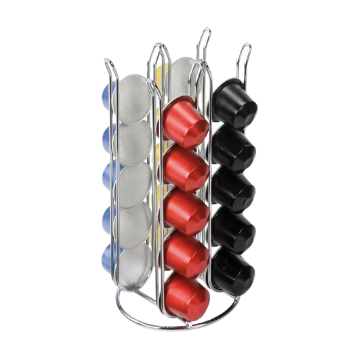 Supporto cilindrico metallico con capsule da caffè rotonde in argento, rosso, nero e blu su sfondo bianco.