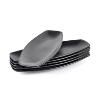 Set d'assiettes ovales noires en céramique, empilées soigneusement ; l'assiette supérieure est inclinée par rapport aux autres.