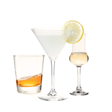 Tre bicchieri trasparenti di vetro con drink: uno tumbler con liquido ambrato, uno da cocktail con fetta di