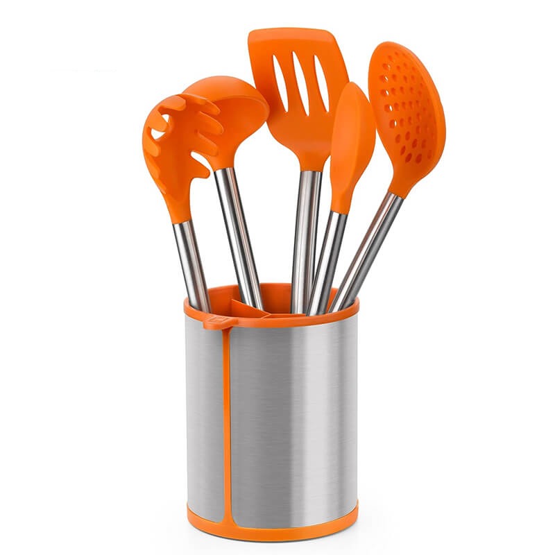 Set di utensili da cucina in silicone arancione con manici in acciaio inox, alloggiati in un portautensili metallico.