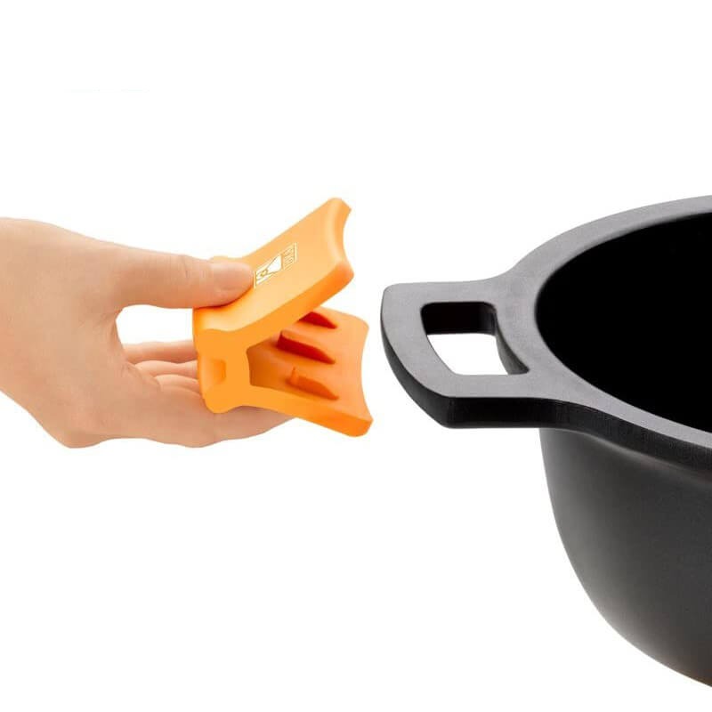 Ein orangefarbener Silikonhandschuh wird von einer Hand neben einem schwarzen Topf mit Griffen gehalten.