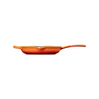 Poêle de couleur orange avec bord ondulé et long manche, sur fond blanc.