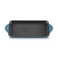 Teglia rettangolare blu con scanalature interne, maniglie ai lati, superficie nera antiaderente.