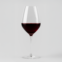 Verre à vin en verre transparent avec vin rouge foncé, sur fond gris clair neutre, forme élégante et fine.