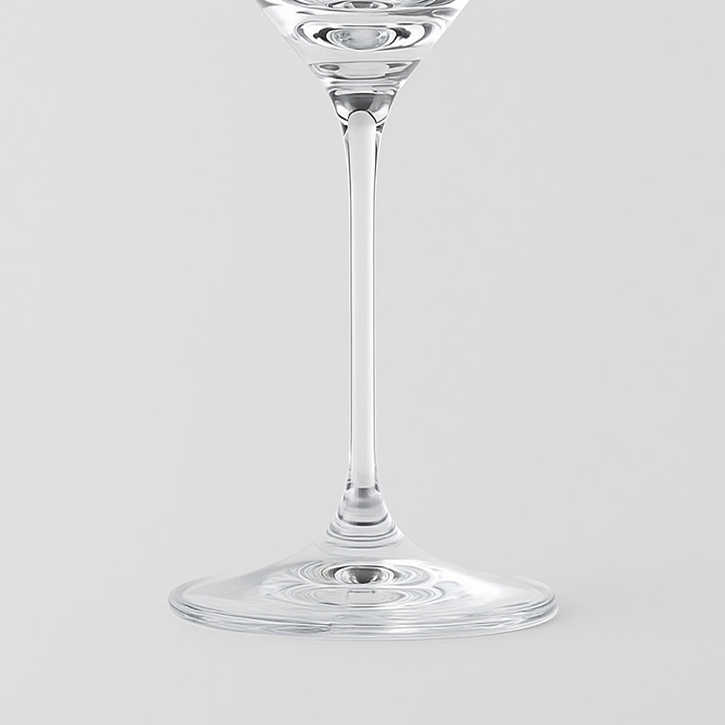 Verre à vin en verre transparent à tige fine et base ronde sur fond gris clair
