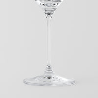 Verre à vin en verre transparent à tige fine et base ronde sur fond gris clair