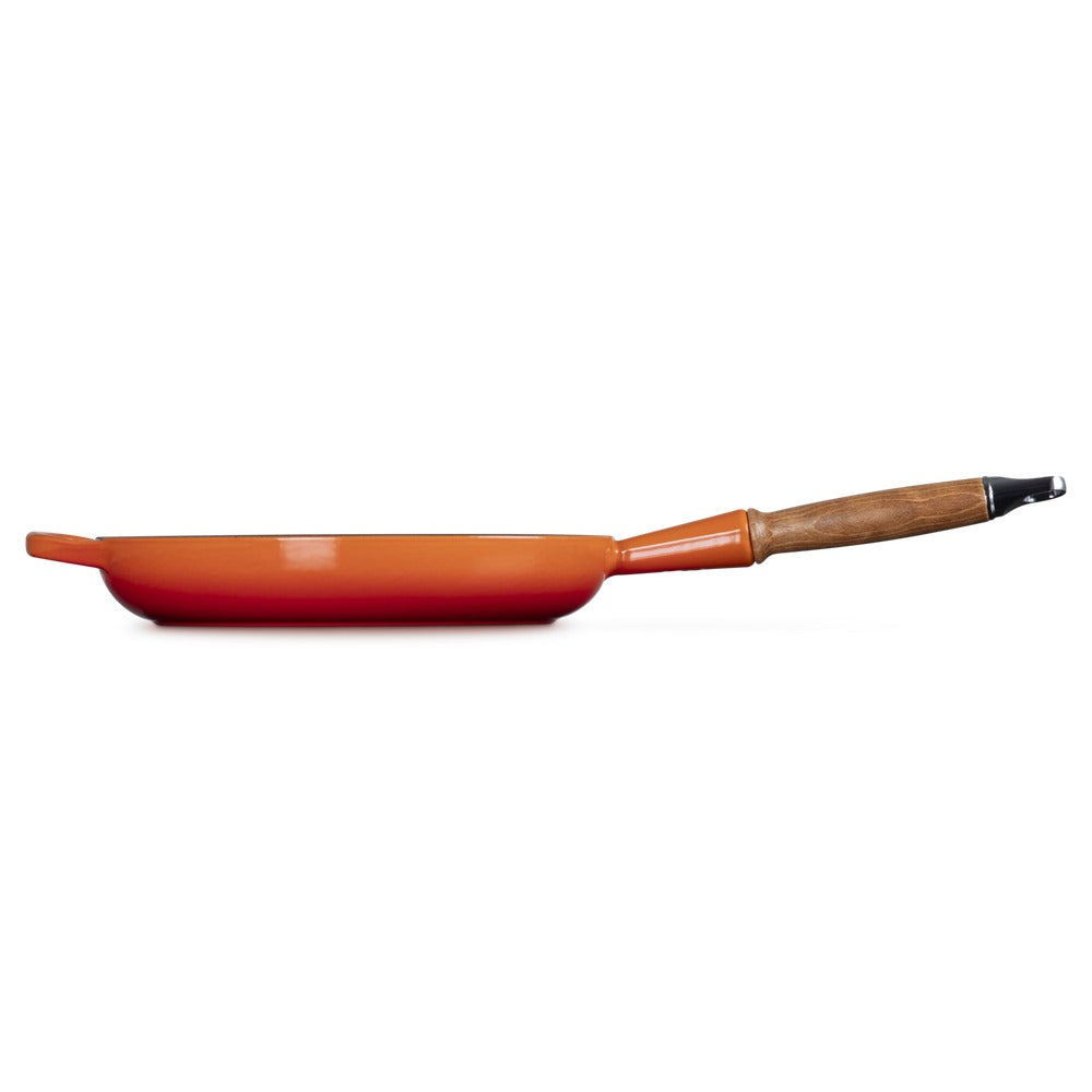 Ronde oranje koekenpan met houten handgreep, glad oppervlak en afgeronde randen, op witte achtergrond.