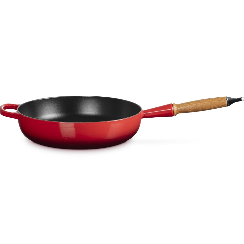 Padella rotonda con manico in legno, esterno rosso lucido e interno nero opaco, su sfondo bianco.
