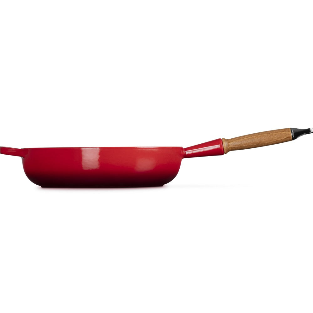 Padella rossa con manico in legno, di forma circolare e materiale metallico, su sfondo bianco.