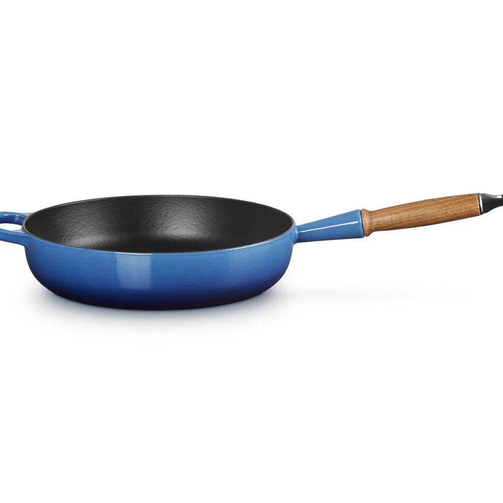 Padella circolare con manico in legno, di colore blu esterno e interno nero, su sfondo bianco.