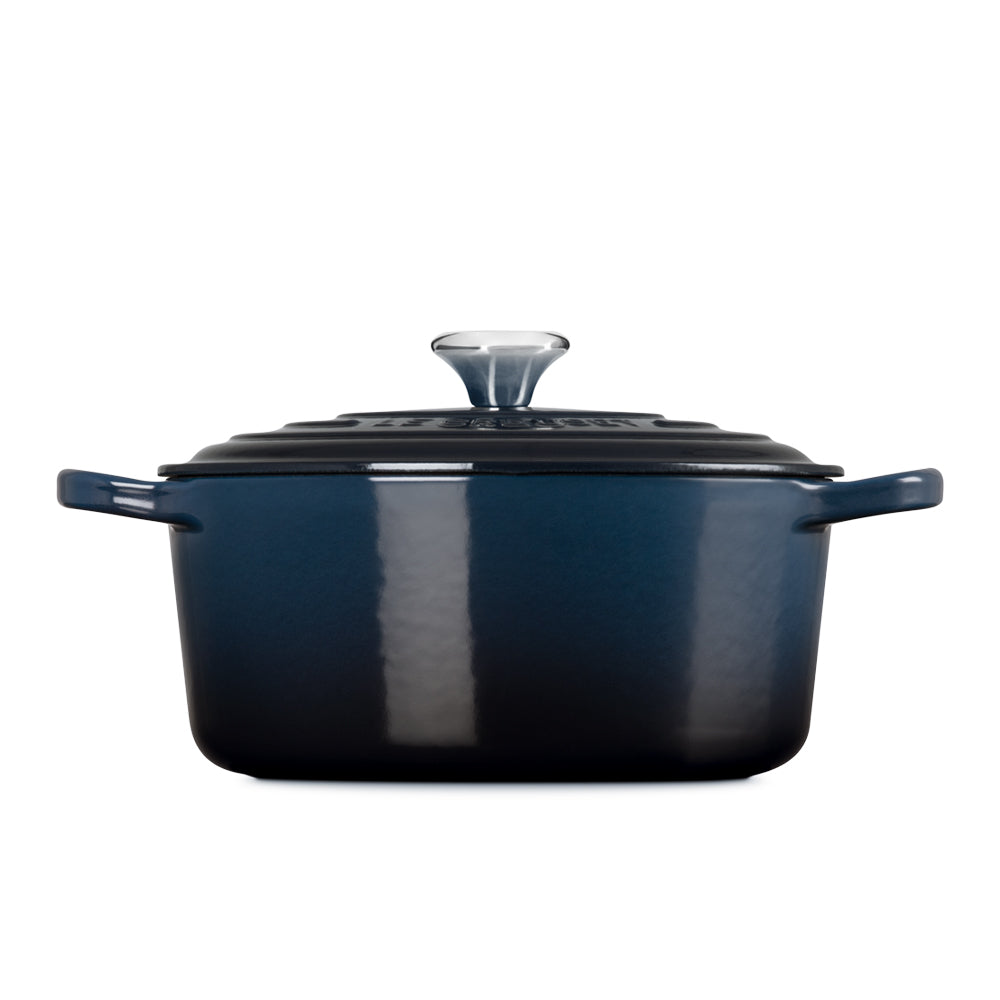 Pentola rettangolare in ghisa smaltata blu con coperchio nero e manici laterali, su sfondo bianco.