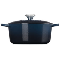 Dark blue rectangular enameled cast iron pot with black lid and steel handle, on white background