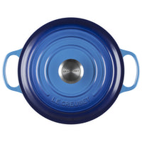 Blue round enameled cast iron cocotte with double handle, domed lid with dark rim and stainless steel knob with Le Creuset lettering.