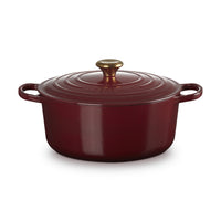 Casserole red with lid, brass handle, smooth glossy surface, shape round, neutral setting.
