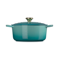 Braadpan in blauw-turquoise met deksel en gouden handgreep, matte afwerking.