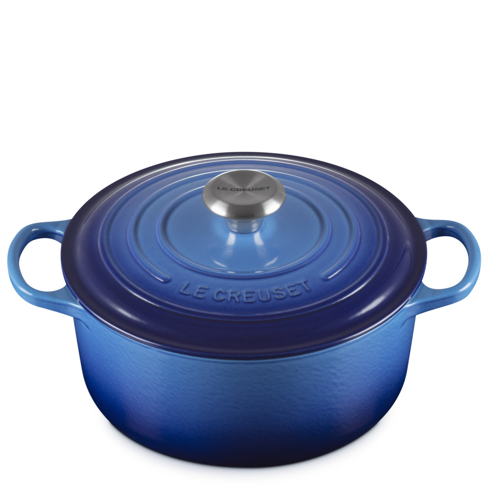 Blauwe geëmailleerde gietijzeren pan met deksel, zijhandgrepen en centrale metalen knop met opschrift Le Creuset, witte achtergrond