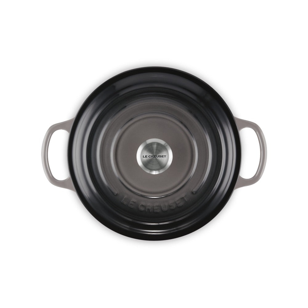 Zwarte geëmailleerde gietijzeren pan met handgrepen, gemarkeerd "LE CREUSET" in het midden. Elegante glanzende bodem.