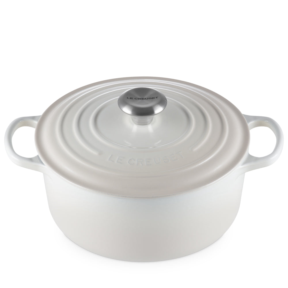 Witte ovale geëmailleerde gietijzeren pan met deksel, zijhandgrepen en metalen knop, merk Le Creuset zichtbaar op deksel.