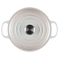 Rond beige keramisch deksel met centraal satijnen stalen handvat met Le Creuset opschrift, witte zijhandvatten.