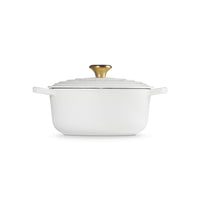 White oval pot with lid, gold handle and smooth surface. Elegant minimalist design.