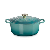 Oval enamelled cast iron casserole, turquoise colour gradient, with lid a golden handle and side handles.
