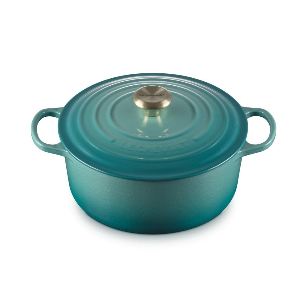 Turquoise enamelled cast iron saucepan with lid and golden metal handle. Round design and side handles.