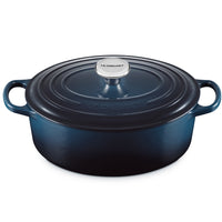 casserole ovale en fonte émaillée bleu avec couvercle a spirale et anses, bouton métallique avec inscription Le Creuset, fond blanc