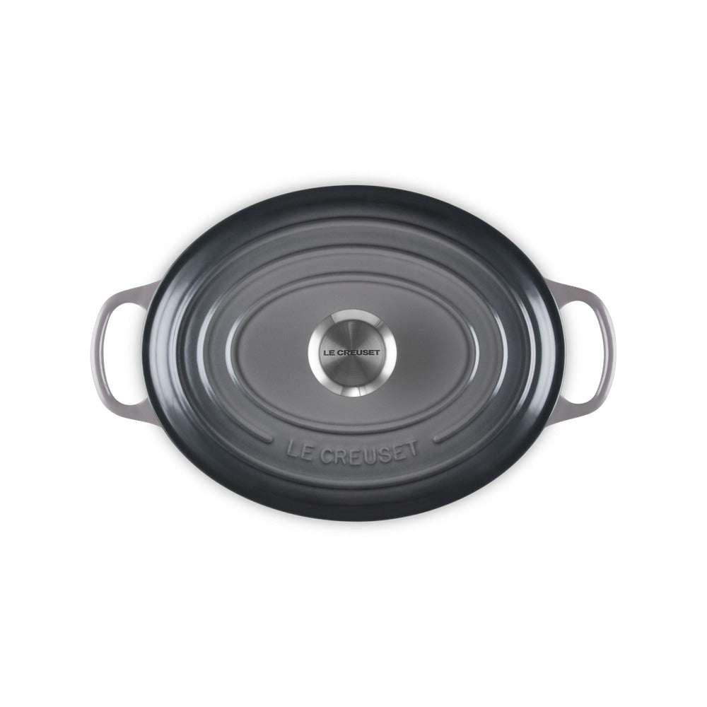 Casserole ovale de couleur gris foncé, en fonte émaillée, avec deux anses et couvercle centrale en acier.